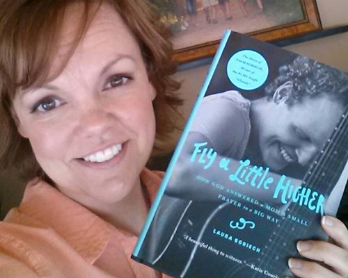 Laura Sobiech holding her book Fly a Little Higher the story of Zach Sobiech