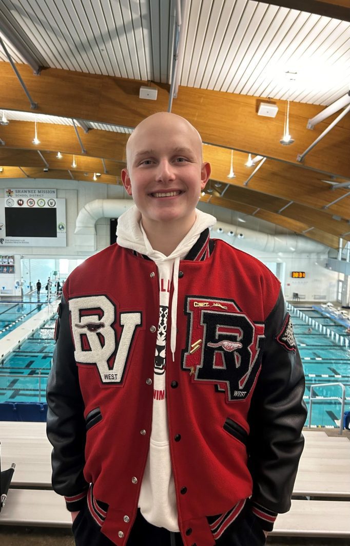 
Jack Punswick standing in front of the school pool in his letterman jacket