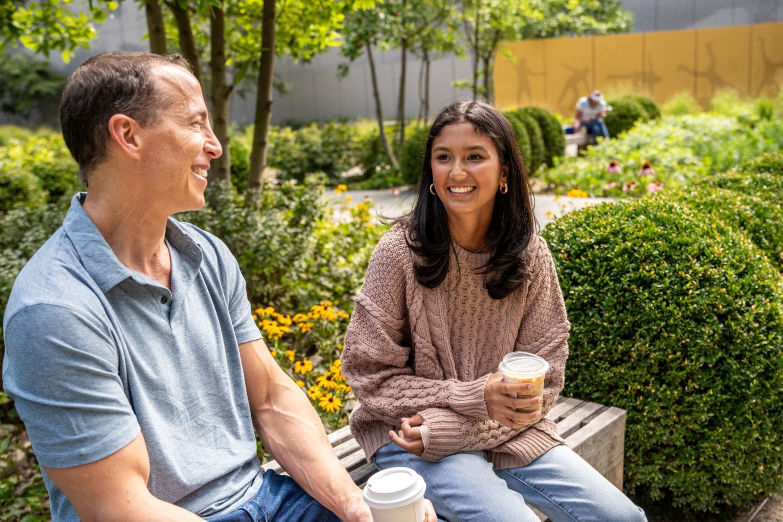 RJ and Lily having coffee on a bench