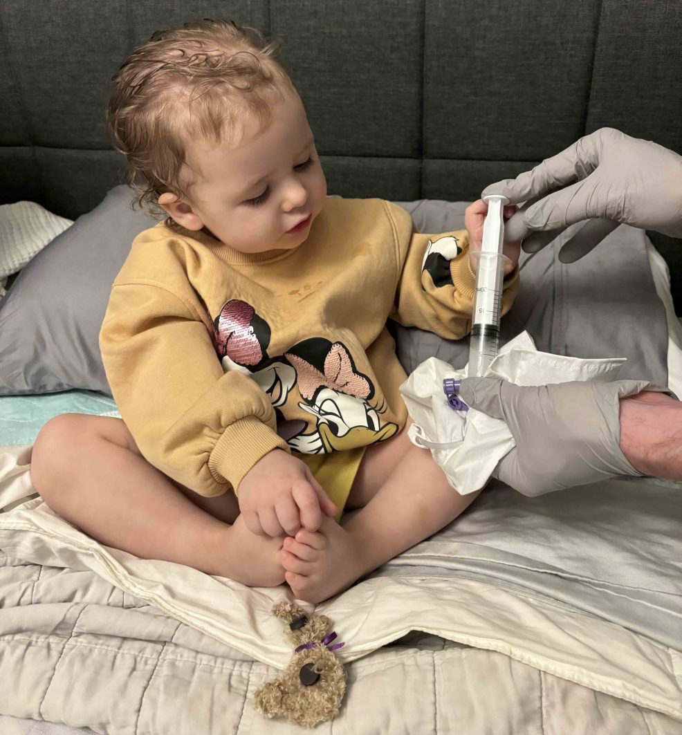 Emma looking at a syringe during treatment