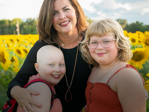 Child affected by cancer and her family posed in a sunflower field