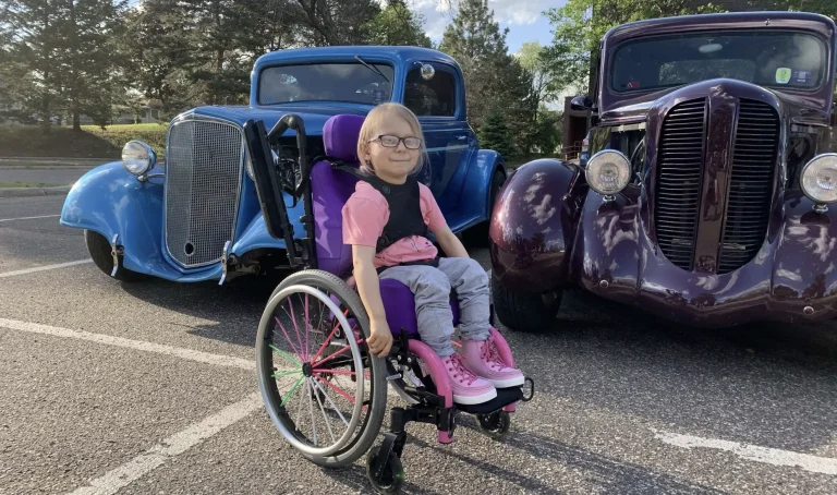 Emma posing for a picture in front of vintage pickup trucks