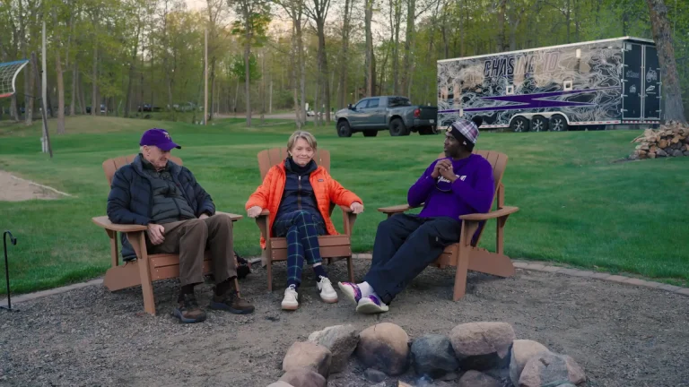 Randy Moss sitting with Norm and Diana Hageboeck around a firepit.